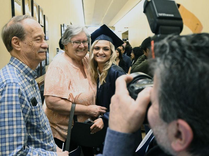 Graduate Hanna Morgan, in cap and gown, pauses for photo opportunities with her grandparents.