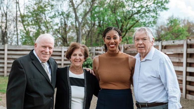 Four individuals stand smiling and posing for photo