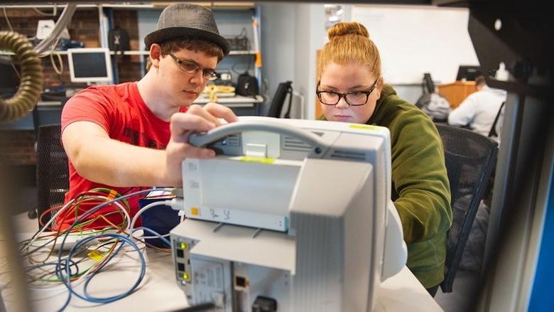 Two students work on hospital equipment in lab